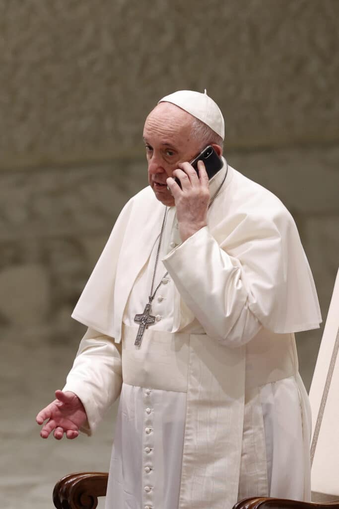 Pope Francis speaks on a cell phone, given to him by his aide Piergiorgio Zanetti,